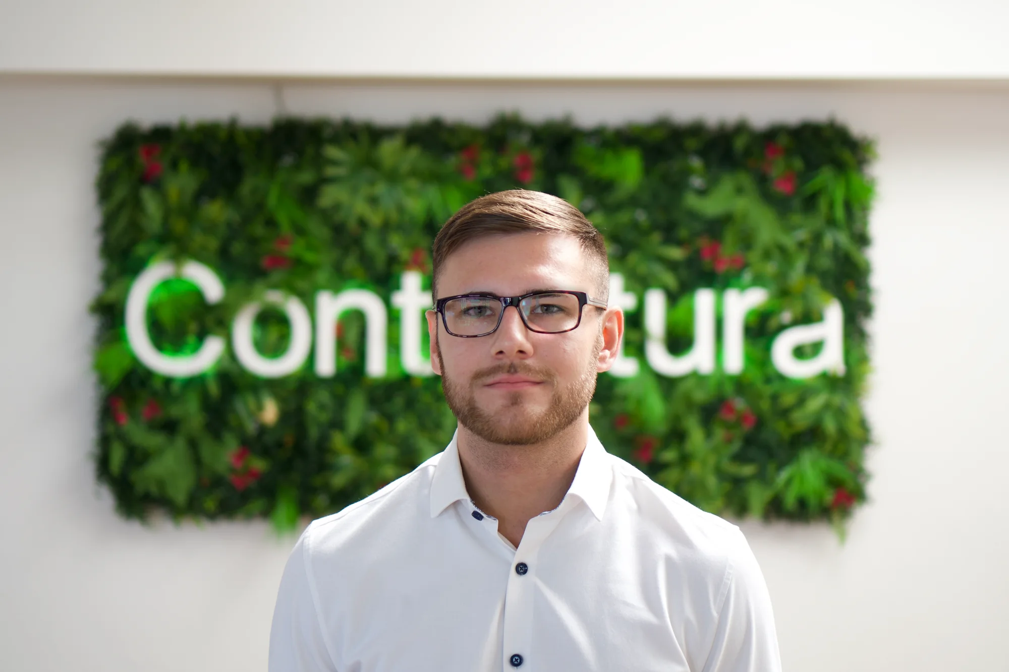 Hannes Henke vor der begrünten Wand mit dem Contentura-Schriftzug